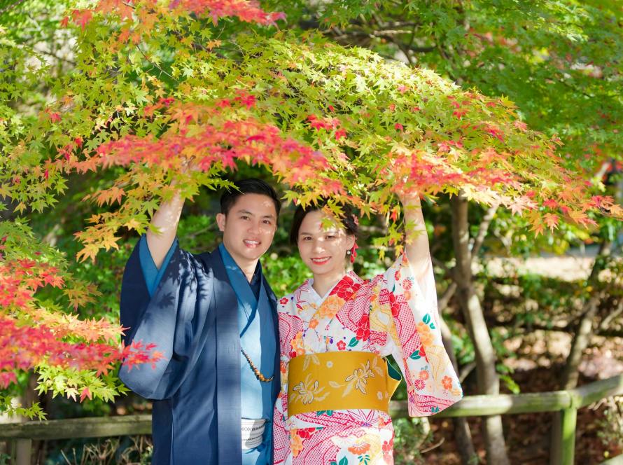woman in kimono standing under red and green leaf tree