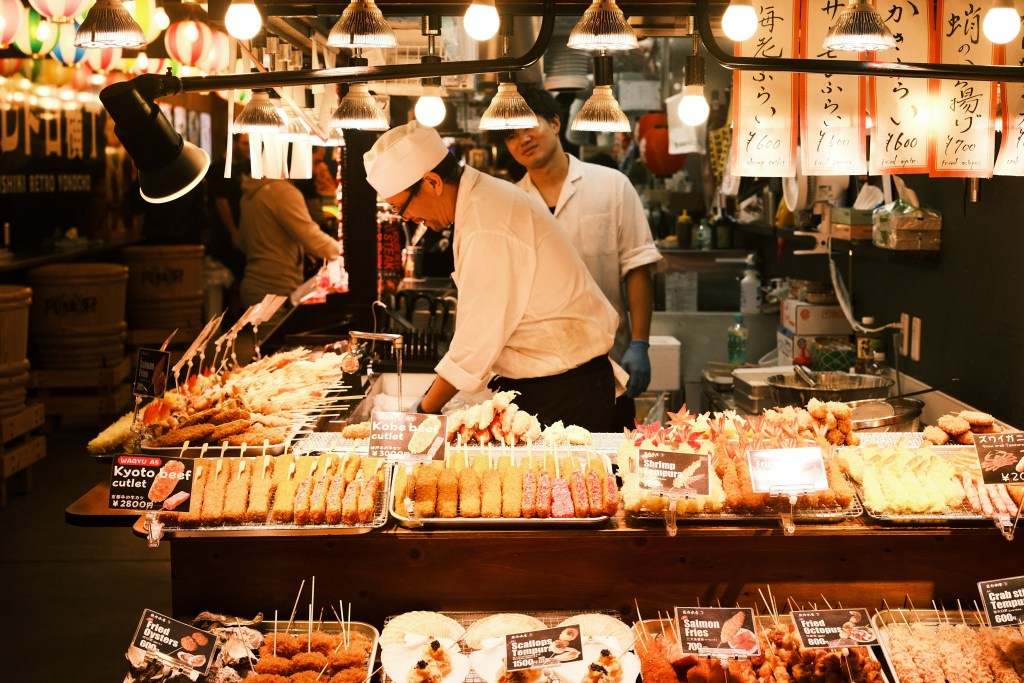 Food vendor selling grilled chicken and seafood skewers at Nishiki Market, a top culinary attraction in Kyoto Japan