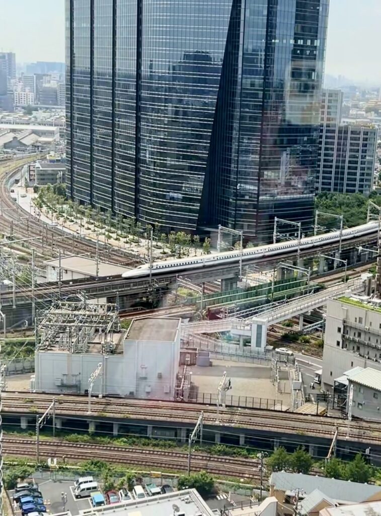 Shinkansen bullet train passing through Tokyo Japan cityscape with glass skyscraper