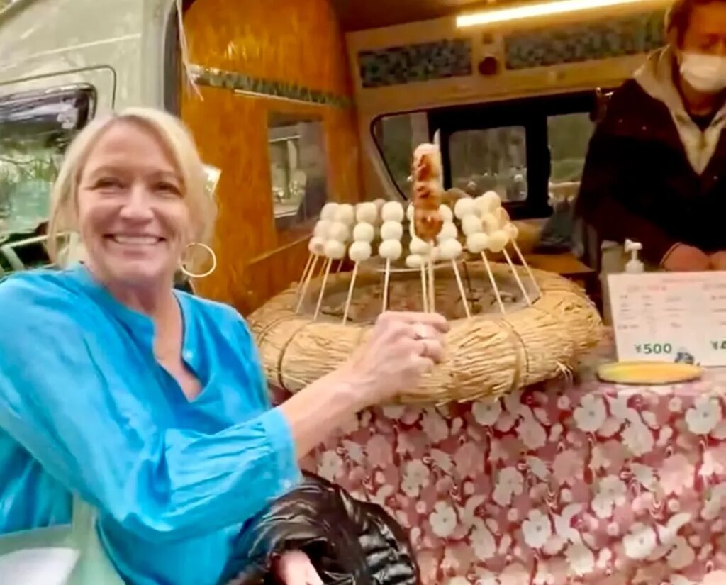 Woman smiling at mochi skewer vendor cart in Yoyogi Park Tokyo Japan