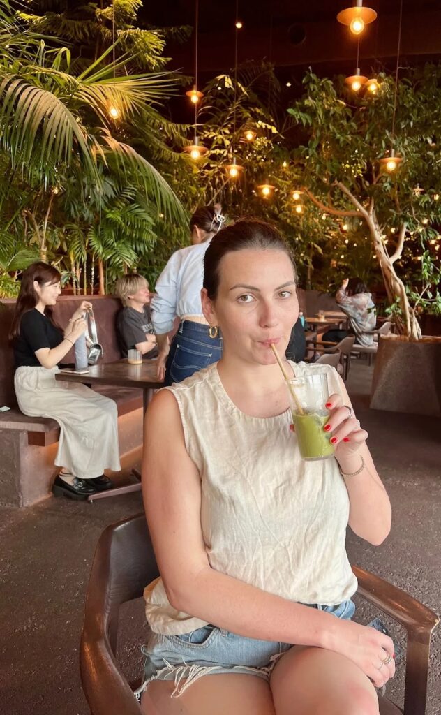 Young woman drinking iced matcha at The Omohara Forest rooftop garden cafe at Tokyu Plaza Omotesando Tokyo Japan